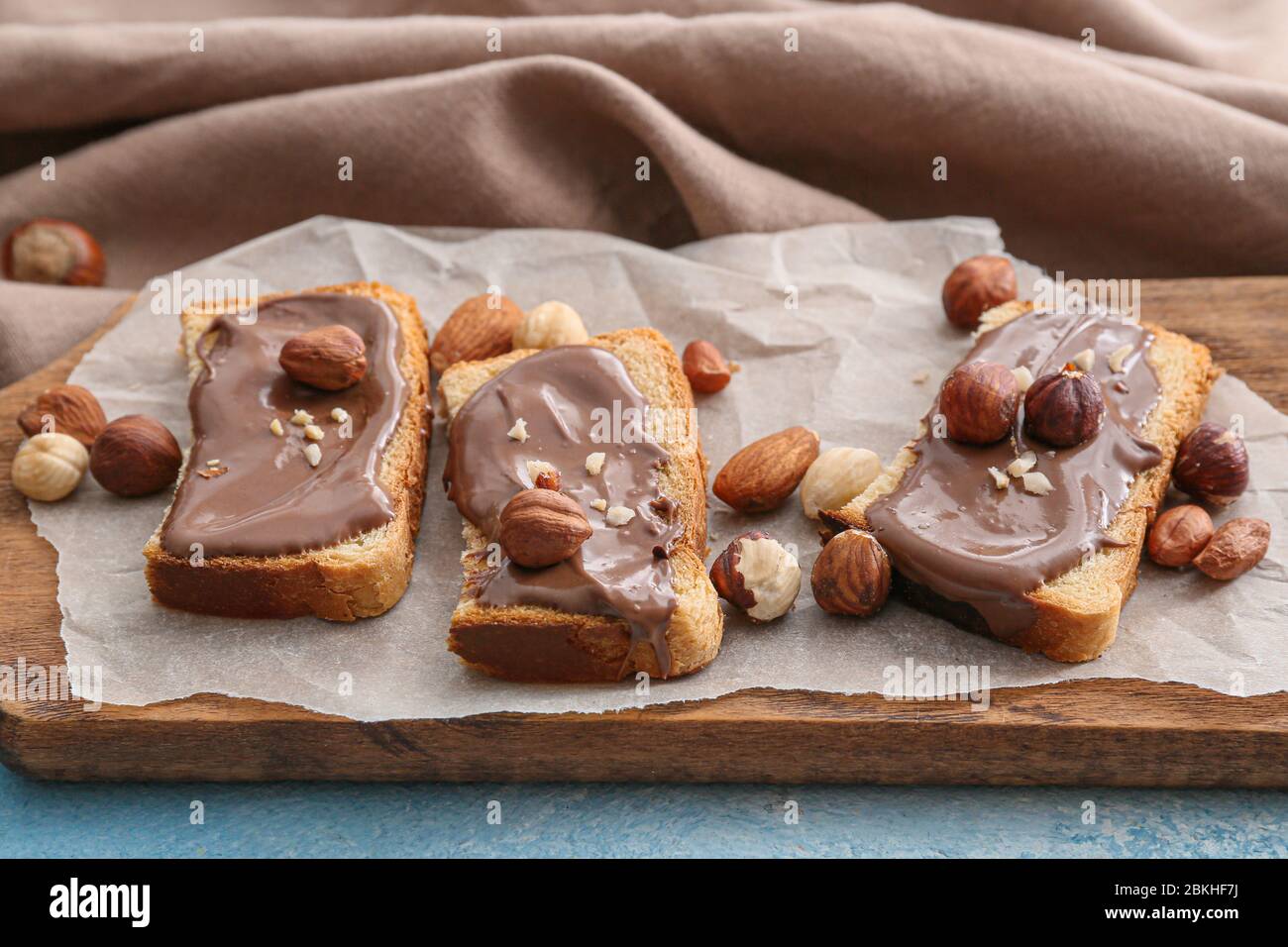 Fresh bread and chocolate paste and nuts on board Stock Photo