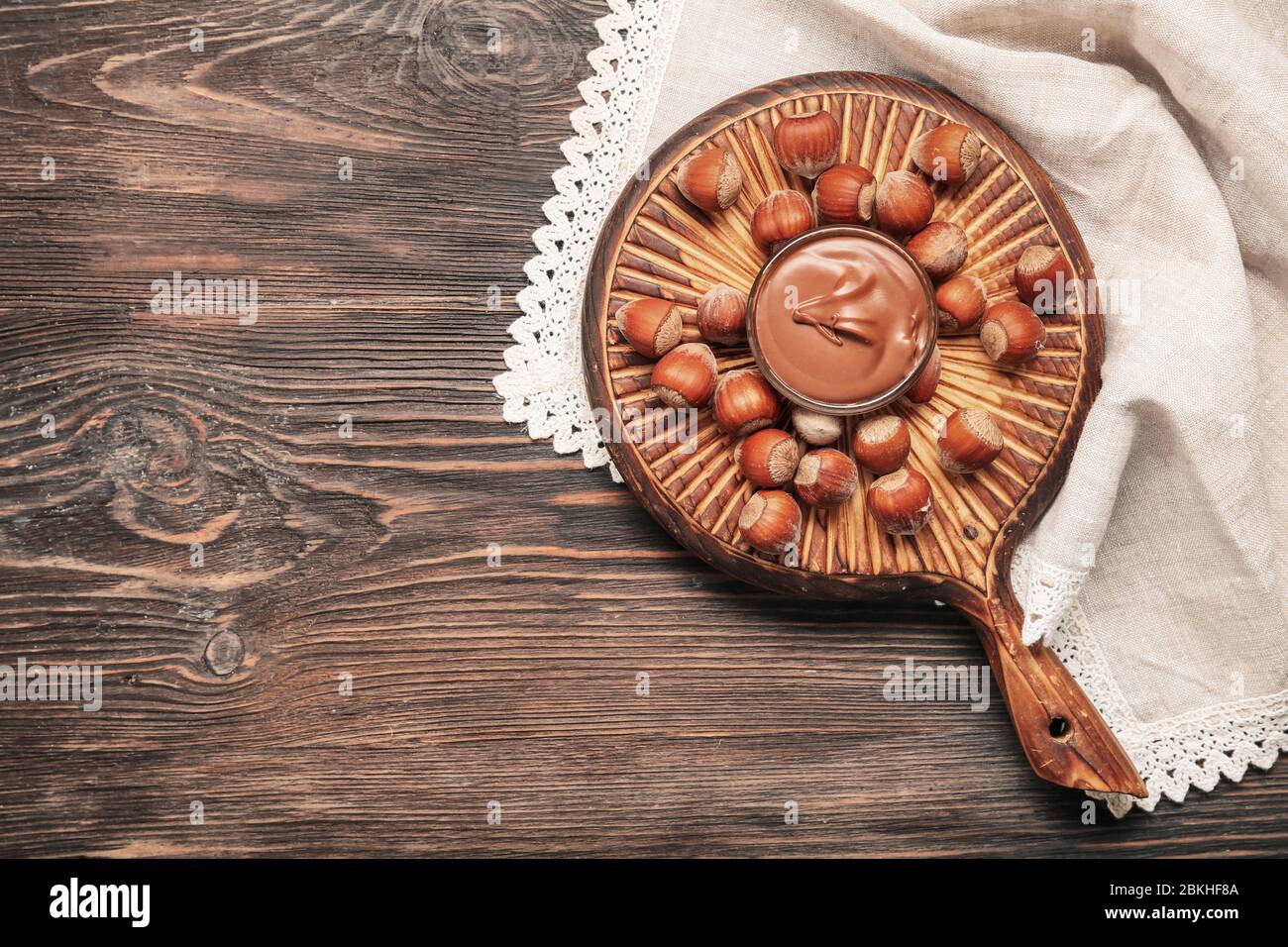 Bowl with tasty chocolate paste and hazelnuts on table Stock Photo