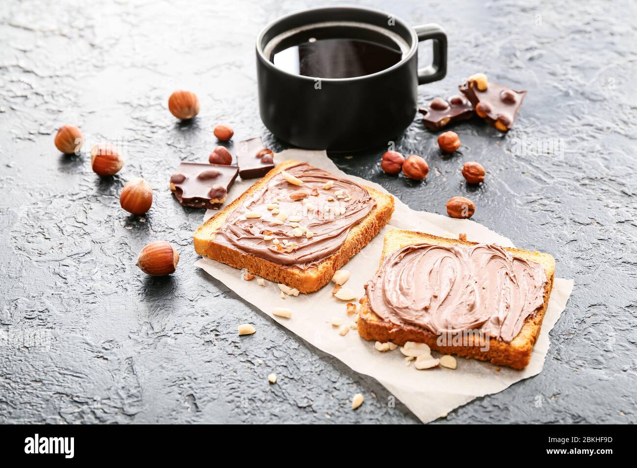 Fresh bread with chocolate paste and cup of coffee on dark background ...