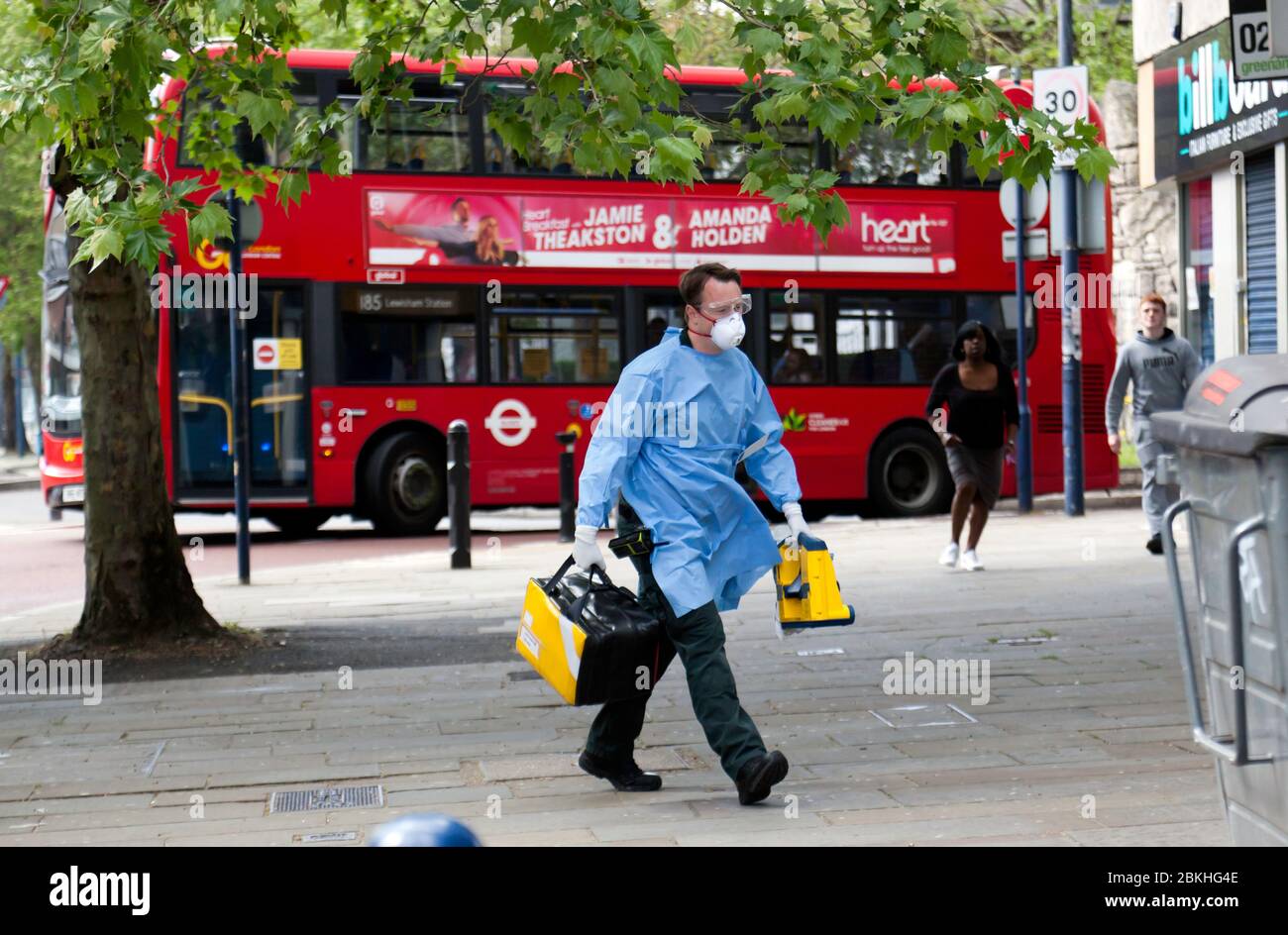 London Ambulance Crewmember, dressed in Personal Protective Equipment, arrives in Lewisham Hight Street, to attend a medical emergency, during the COVID-19 Pandemic Stock Photo