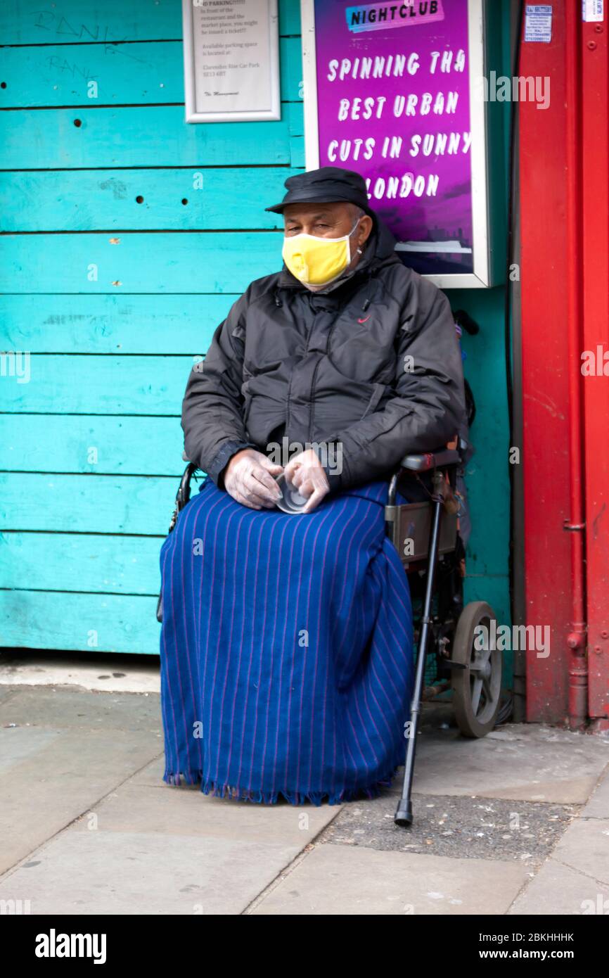 A vulnerable Man in a wheelchair, wearing a face mask, is sitting by