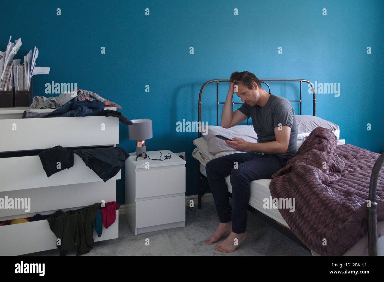 Picture of a man sitting on edge of bed Stock Photo Alamy
