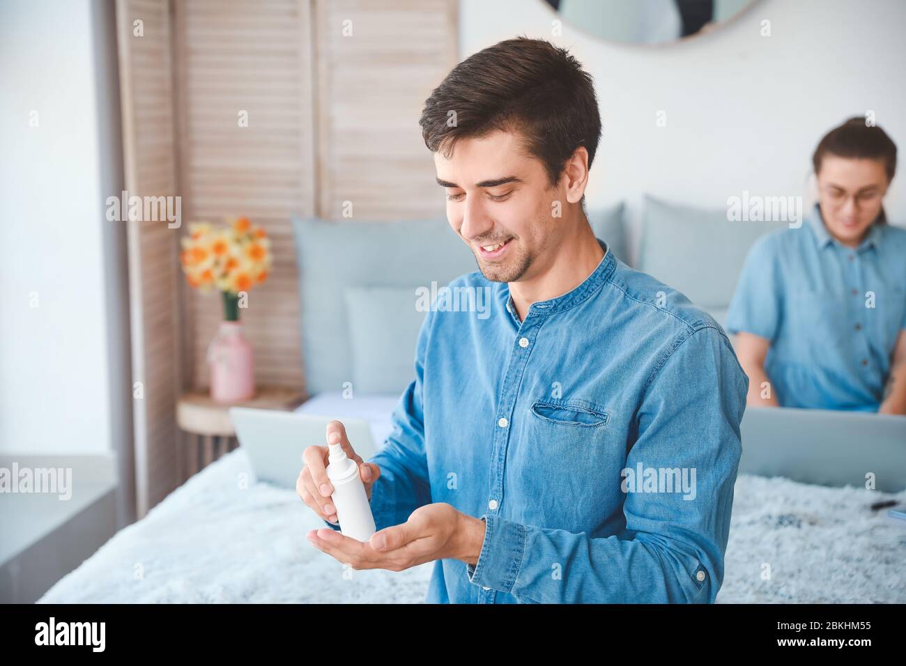 Man applying disinfectant onto hands at home Stock Photo