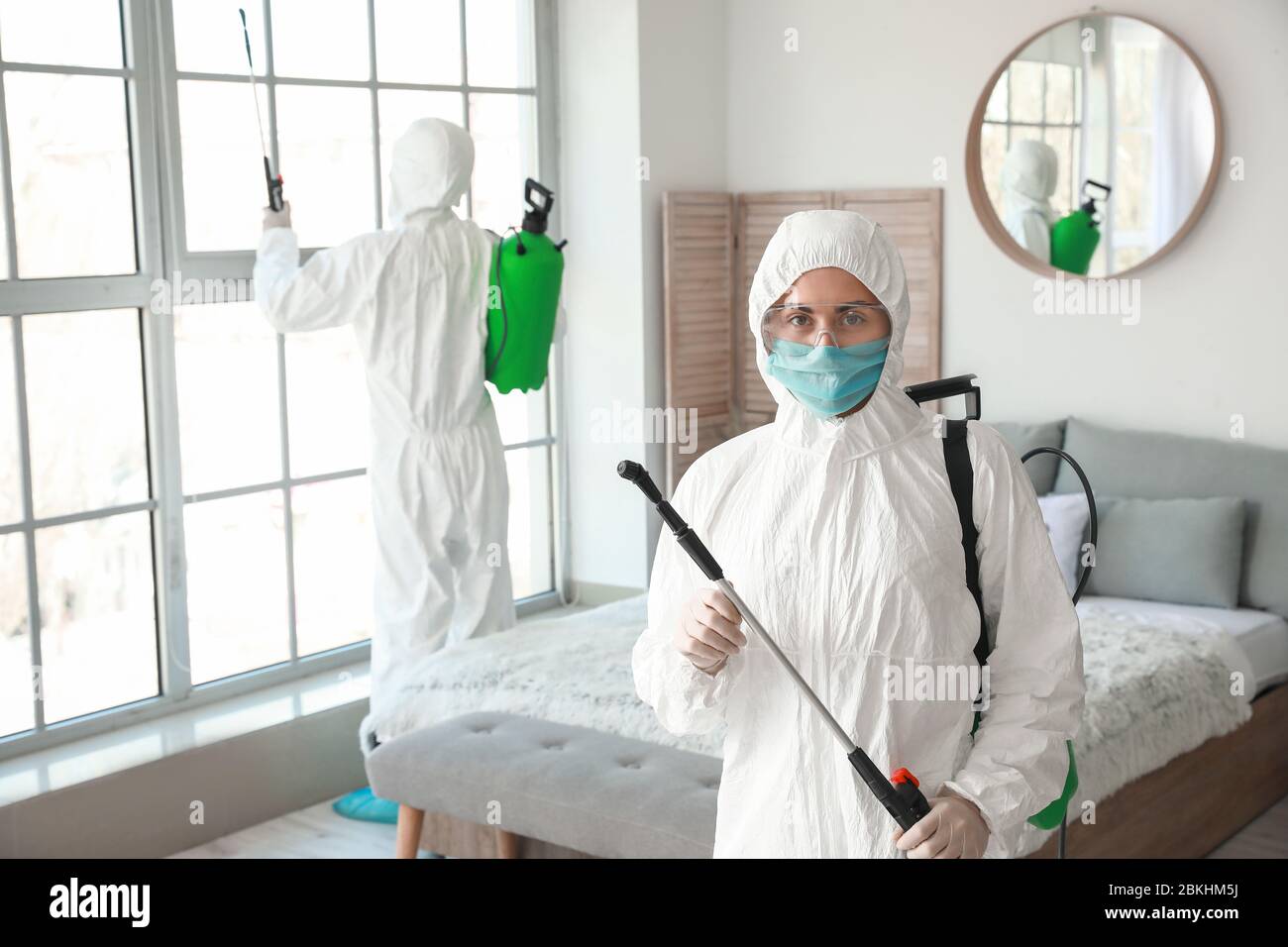 Workers in biohazard suits disinfecting house Stock Photo