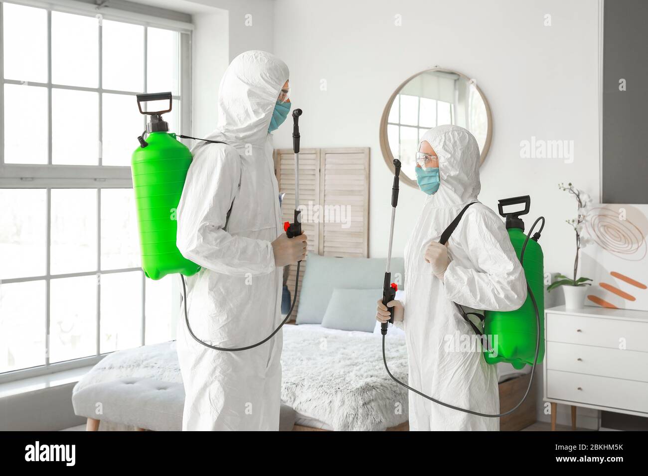 Workers in biohazard suits disinfecting house Stock Photo