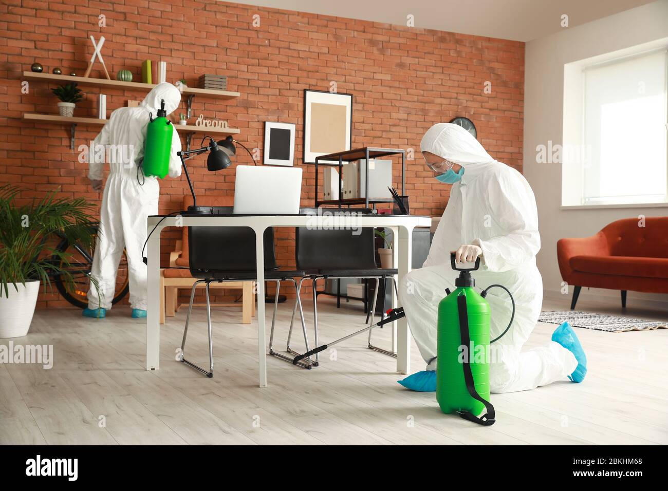 Workers in biohazard suits disinfecting office Stock Photo