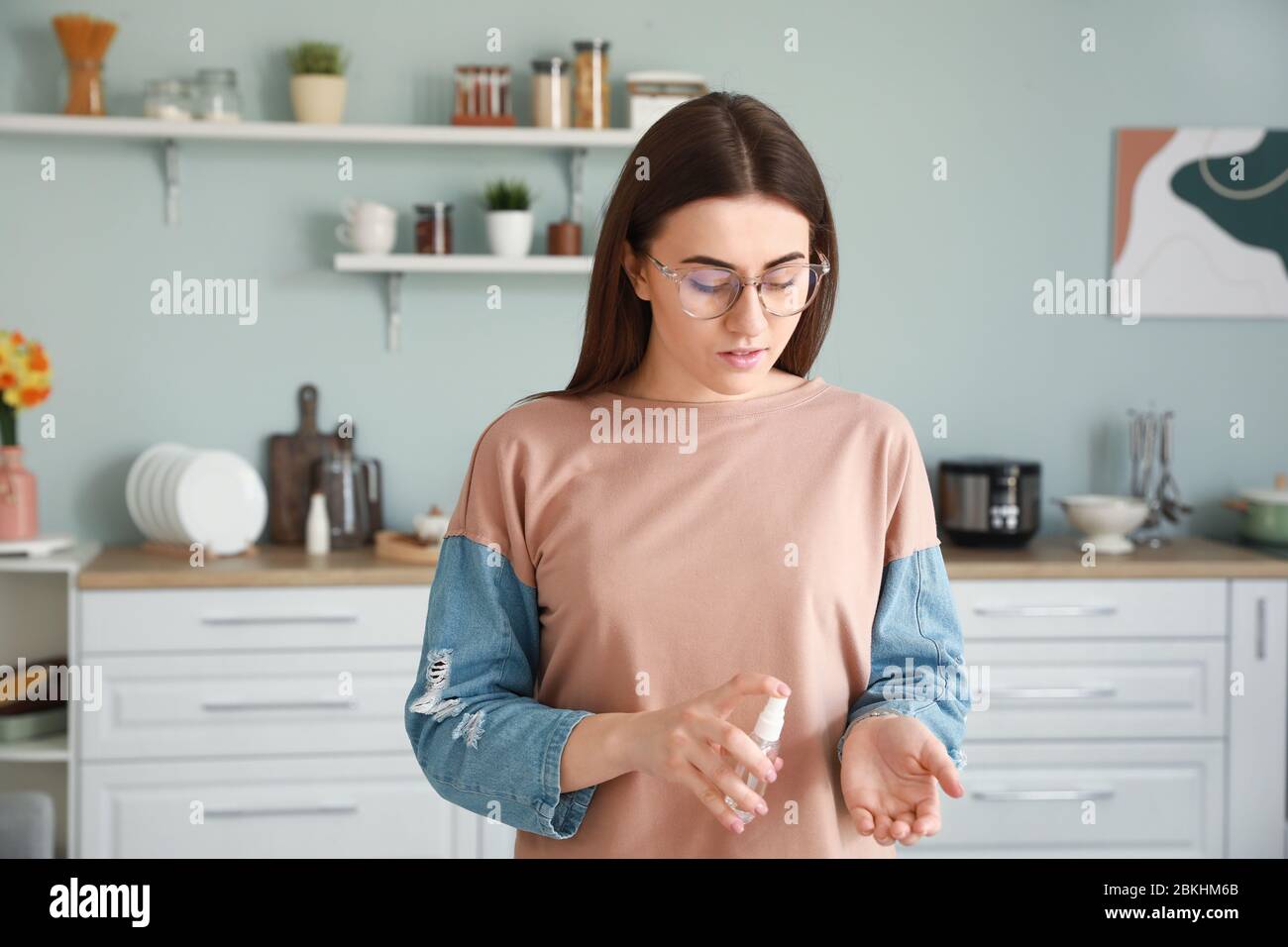 Woman applying disinfectant onto hands at home Stock Photo