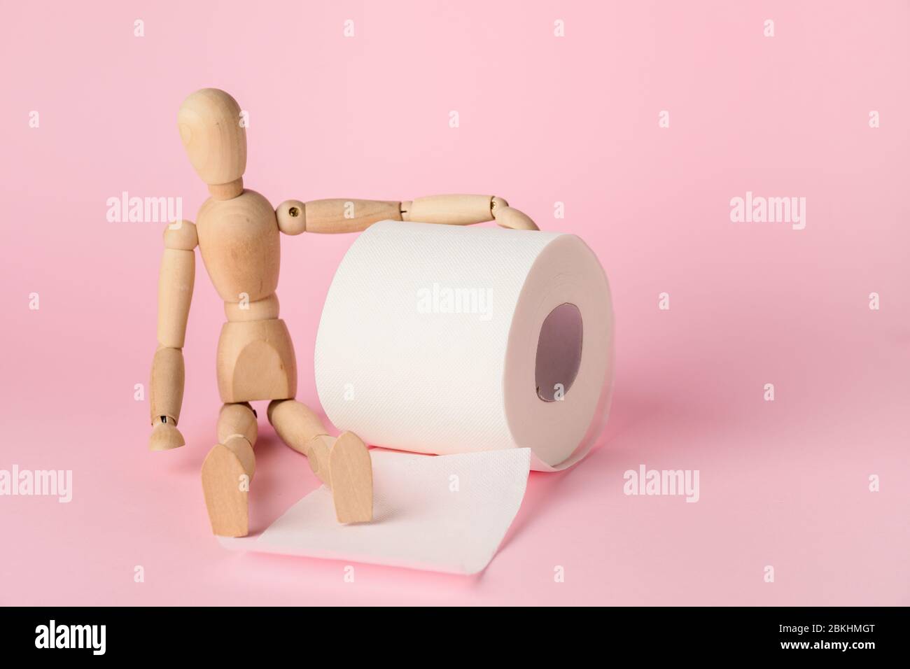 Toilet paper with wooden human figure on color background Stock Photo -  Alamy