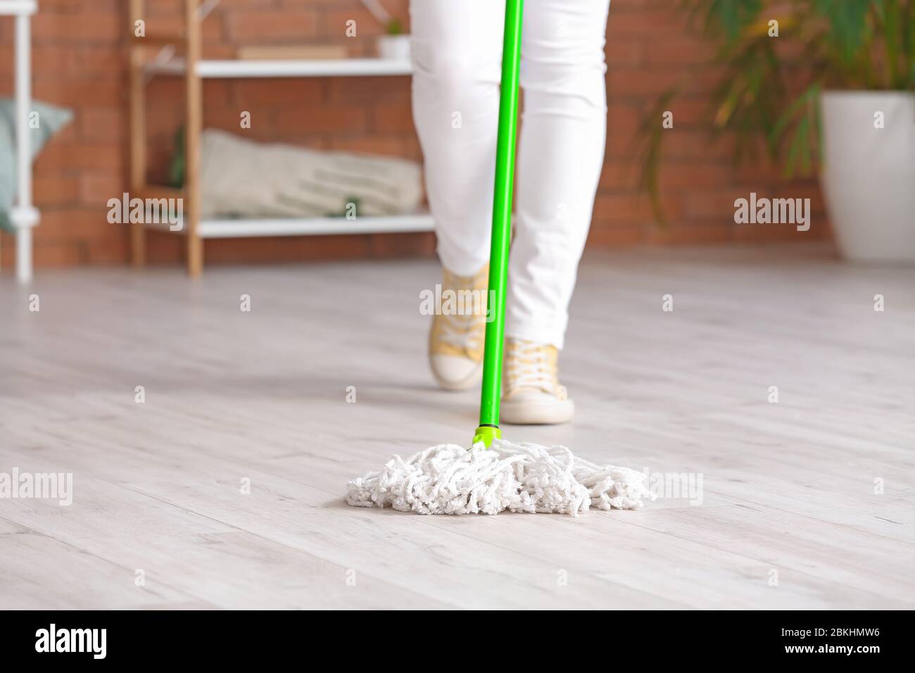 Young woman mopping floor in room Stock Photo