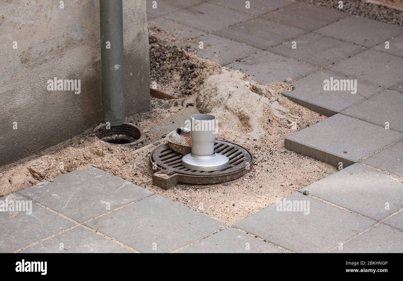 Downspout extensions and repair for better drainage in connection with outdoor garden tiling. Stock Photo