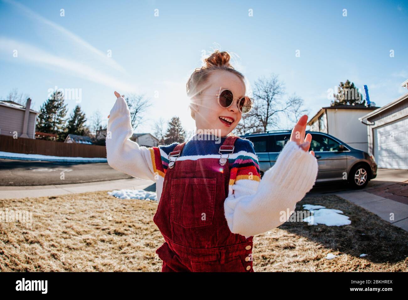 Close up of young girl dancing in front yard with sunglasses on Stock Photo