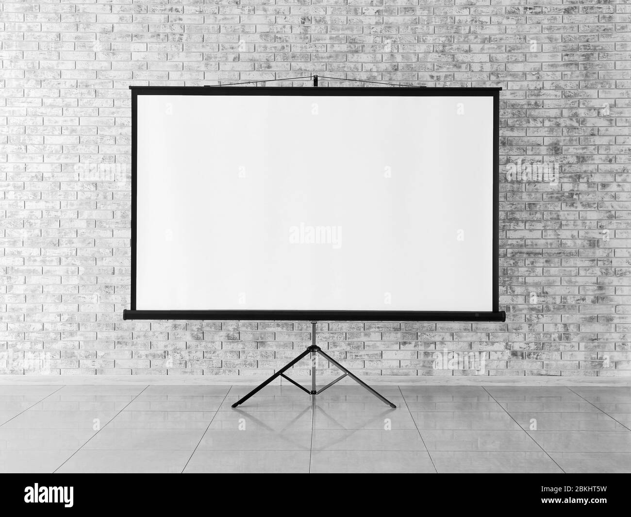 Modern projector screen near brick wall indoors Stock Photo Alamy