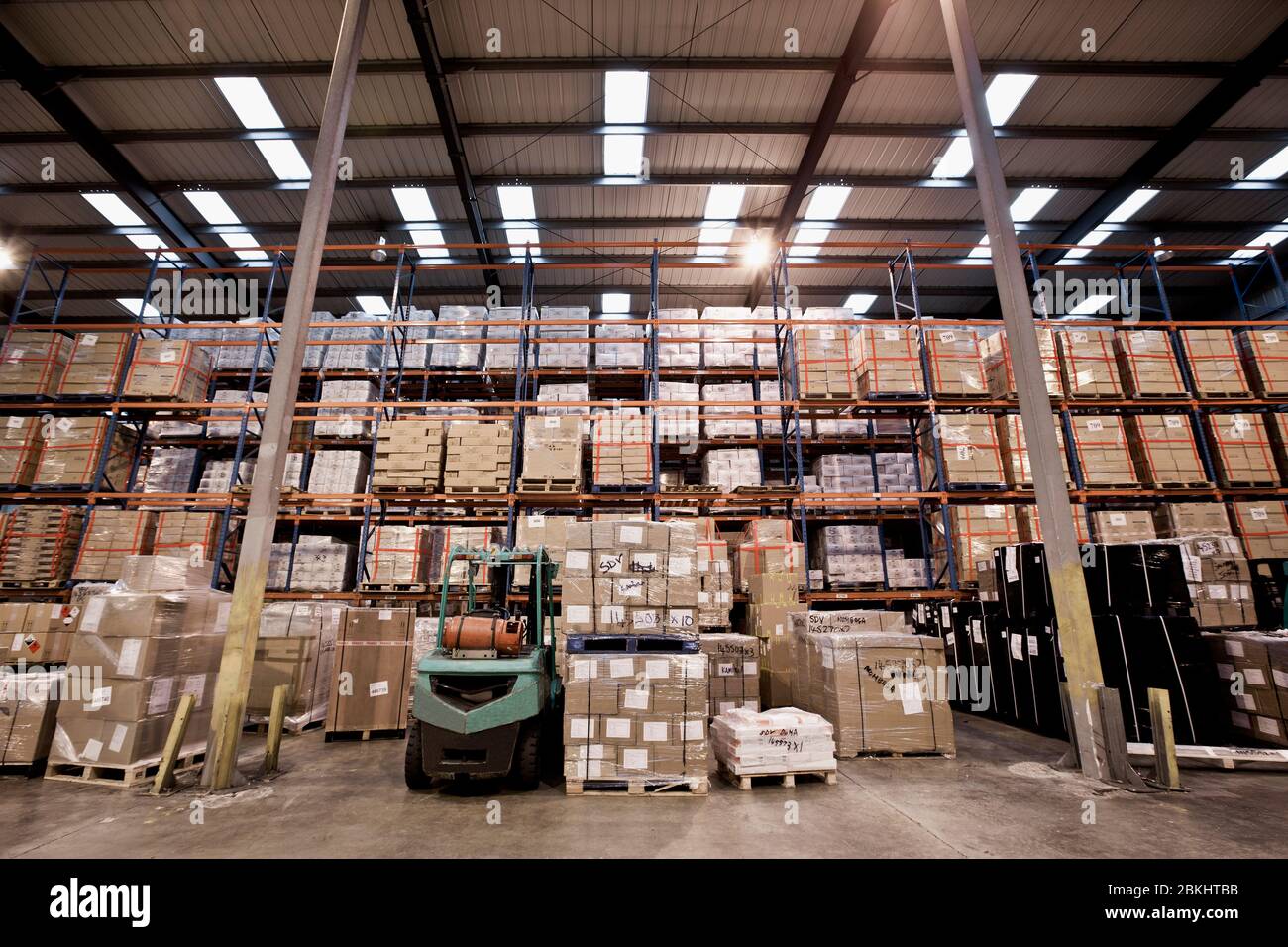 forklift truck parked at fully stocked warehouse in London Stock Photo