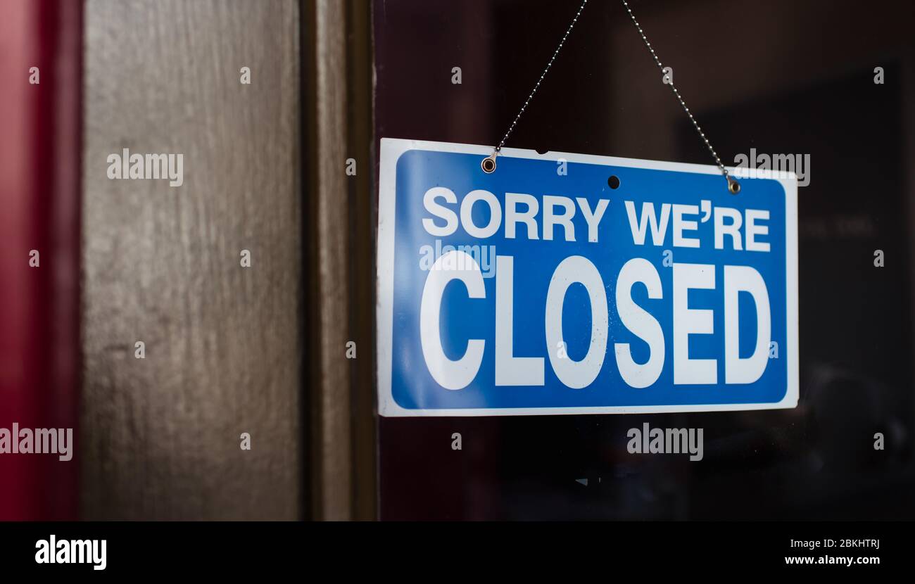 Close up of a closed sign hanging in the window of a store. Stock Photo