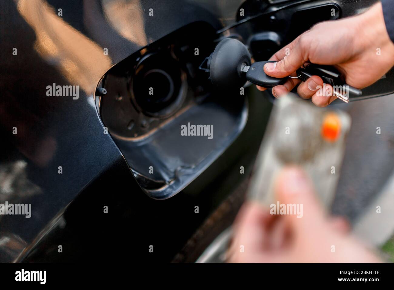 Man with credit card opening fuel tank of his new car. Cashless