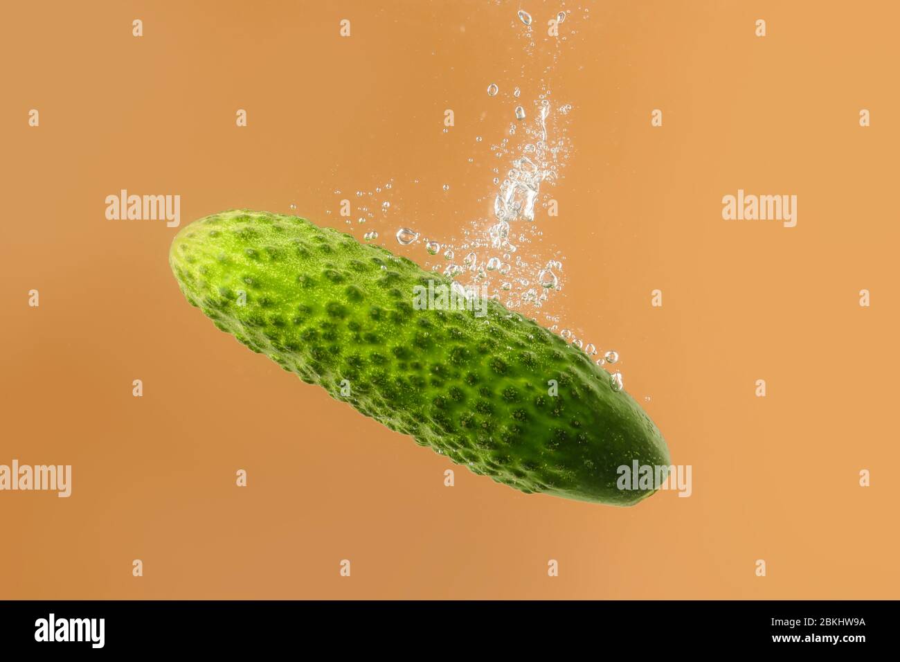 Falling of fresh cucumber into water against color background Stock Photo Alamy