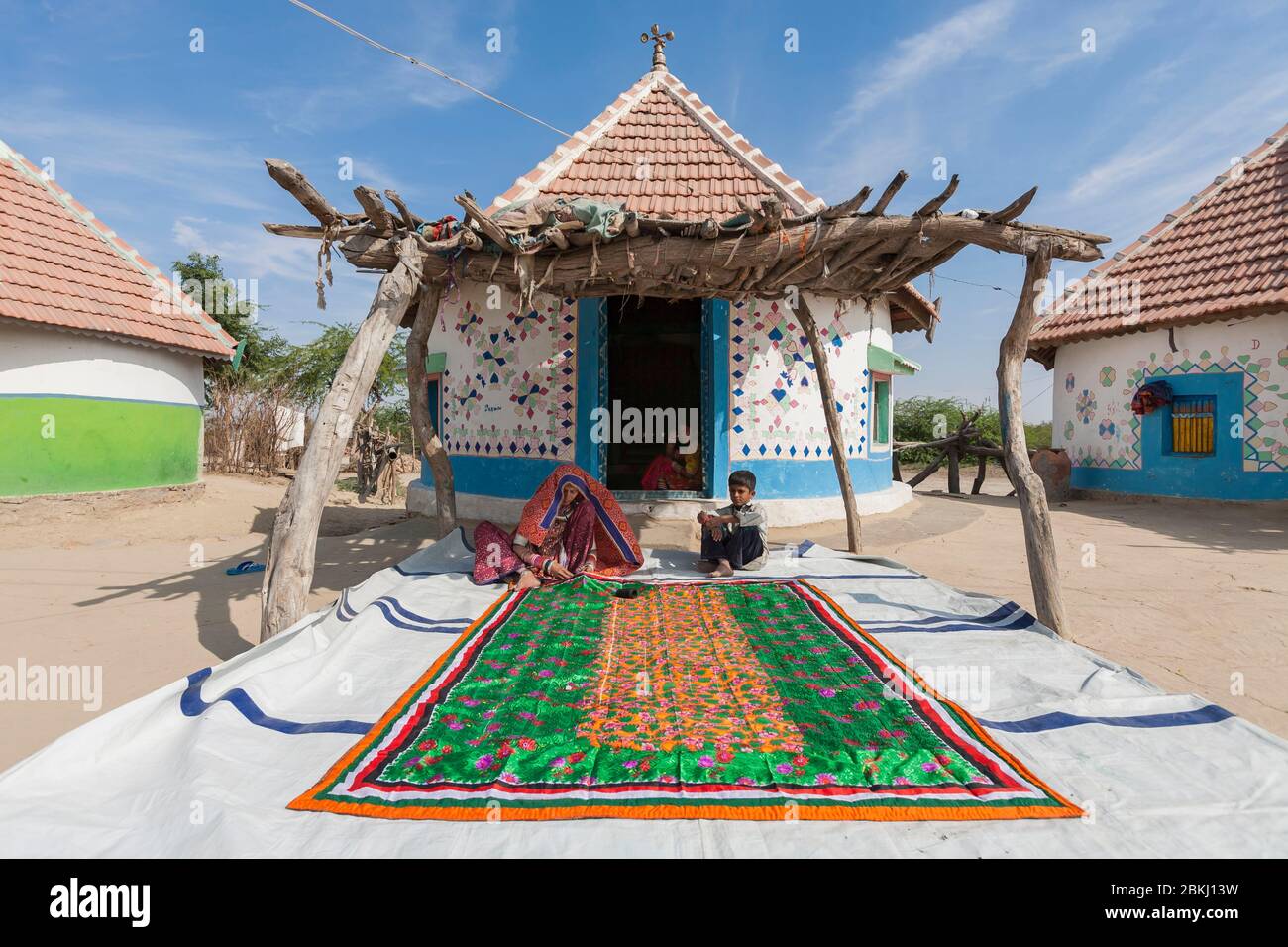 India, Gujarat State, Kutch region, Adipur village, nearby Bhuj city, Meghwal tribal woman wearing traditional embroidered clothes in front of hut decorated with colorful patterns Stock Photo