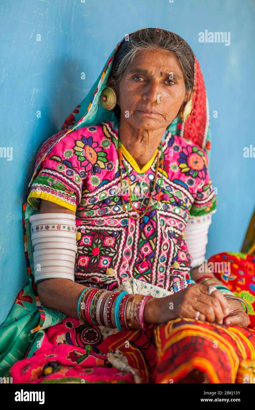 India, Gujarat State, Kutch region, Ludiya village, near Bhuj, Meghwal tribe woman wearing traditional embroidered clothes posing in front of the blue wall of a hut Stock Photo