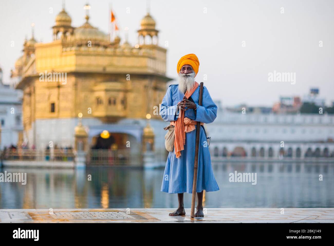 India, Punjab State, Amritsar, Harmandir Sahib, full-length portrait of a Sikh man and Golden Temple in the background, holy place of Sikhism Stock Photo