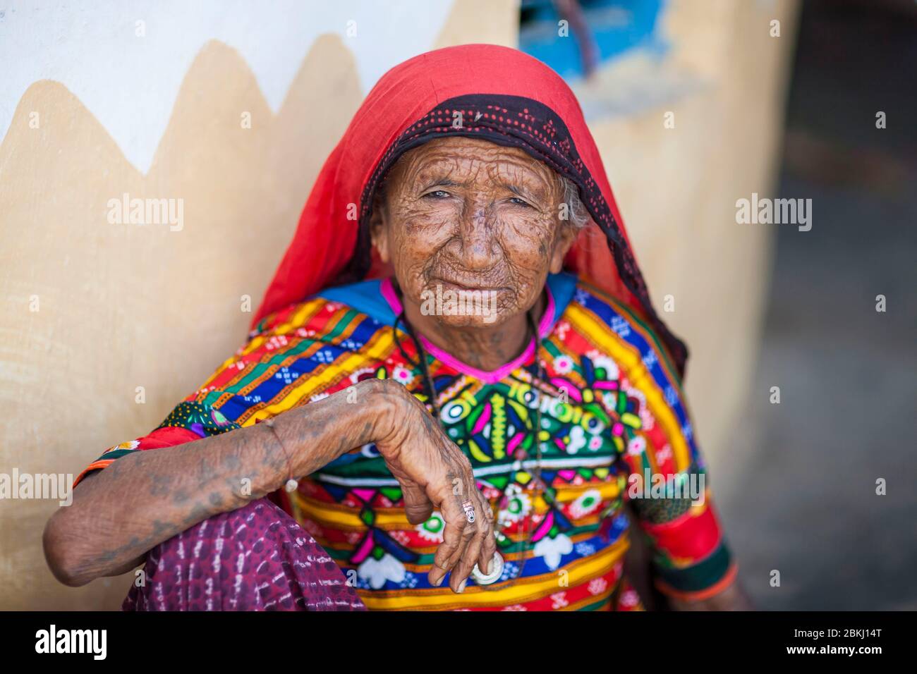 India, Gujarat State, Kutch region, Ludiya village, near Bhuj, portrait of a Meghwal tribe old woman wearing traditional embroidered clothes in front of a decorated hut Stock Photo