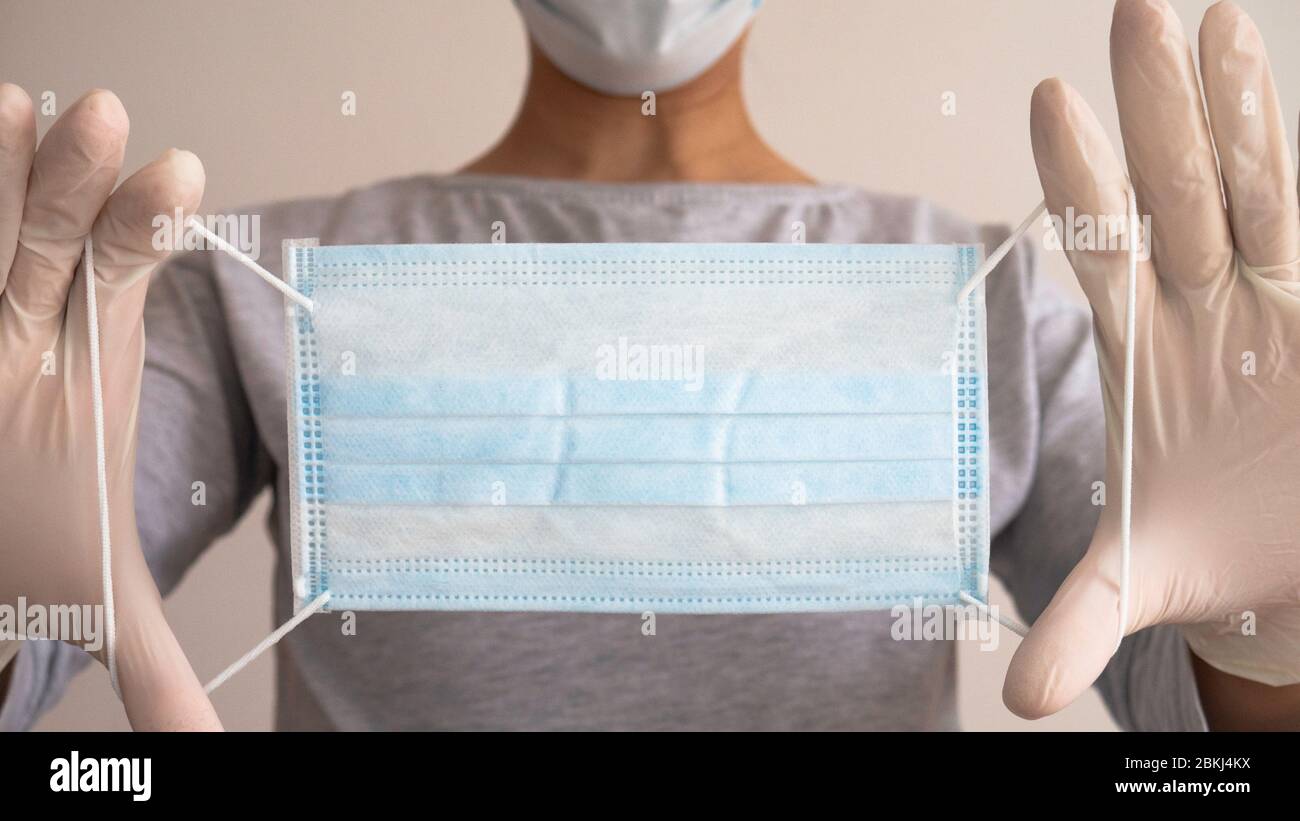 Woman doctor with hands in latex glove holding protective medical white ...