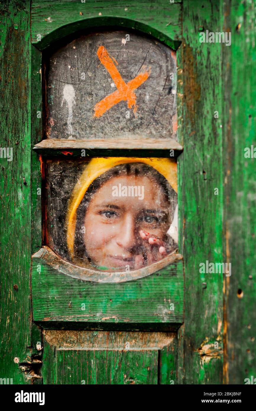 India, Jammu and Kashmir, Pahalgam, India, Jammu and Kashmir, Pahalgam, moving portrait of a girl waving through a green door Stock Photo