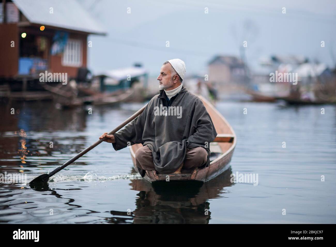 India, Jammu and Kashmir, Srinagar, Dal lake, floating vegetable market, elegant man rowing on a shikara, Kashmiri pirogue, and wearing a pheran, traditional woollen poncho Stock Photo