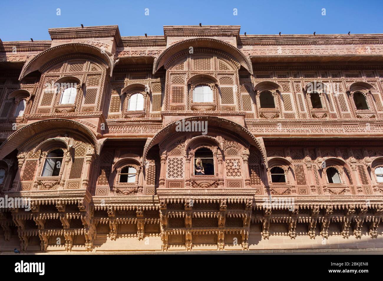 India, Rajasthan, Jodhpur, Fort Mehrangarh, western tourist looking out of the window of a large carved facade Stock Photo