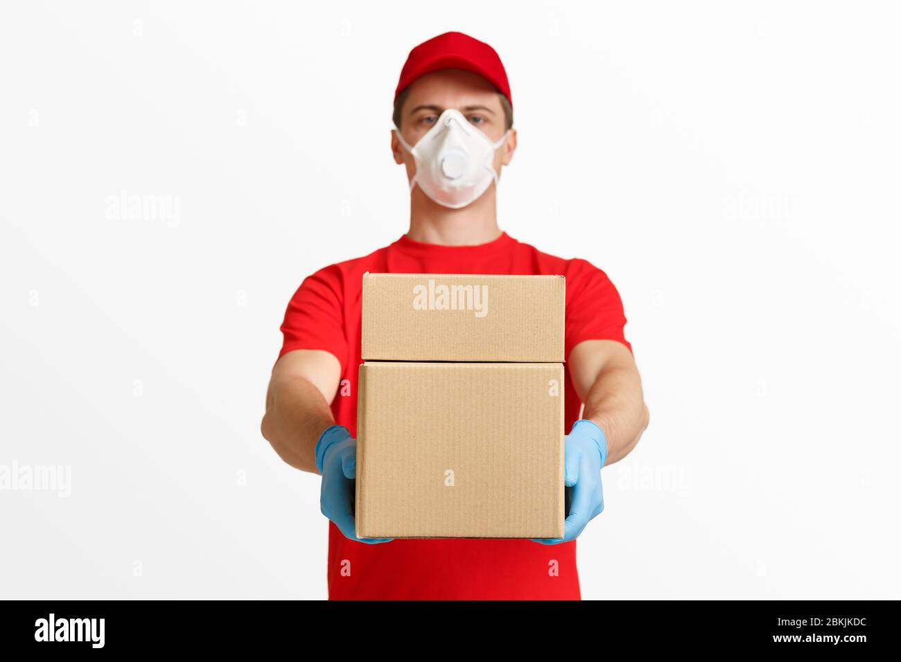 Delivery services. Courier in red uniform gives box Stock Photo