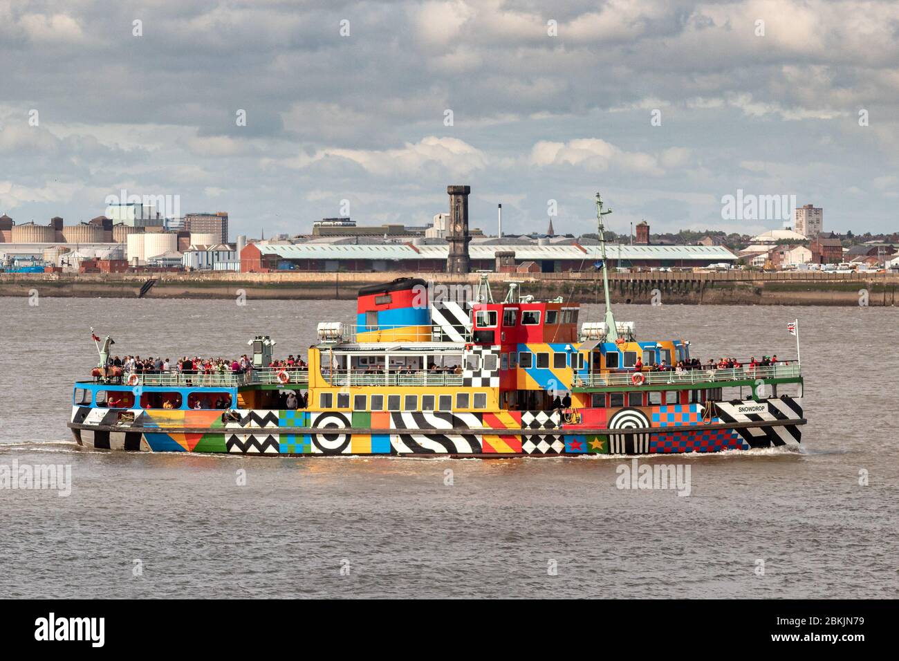 Mersey river ferry 'Snowdrop' in dazzle livery designed by Sir Peter Blake against Liverpool city skyline. Stock Photo