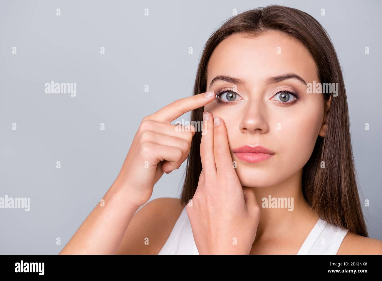 Close up photo of concentrated girl hold small transparent contact lens