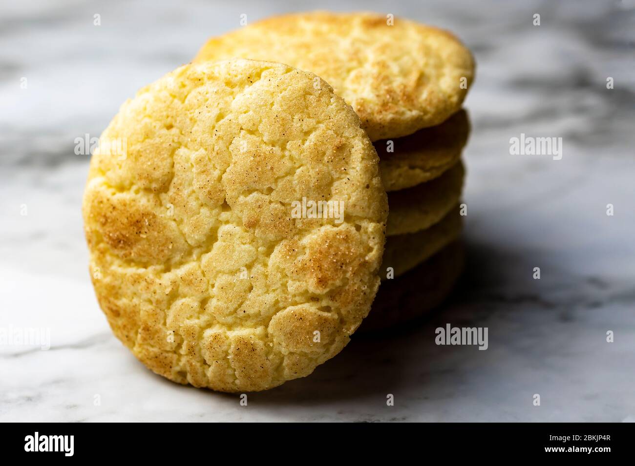 A stack of snickerdoodle cookies on a white and  grey marble surface.  Blurry background.  Close up view of cookie facing camera. Stock Photo