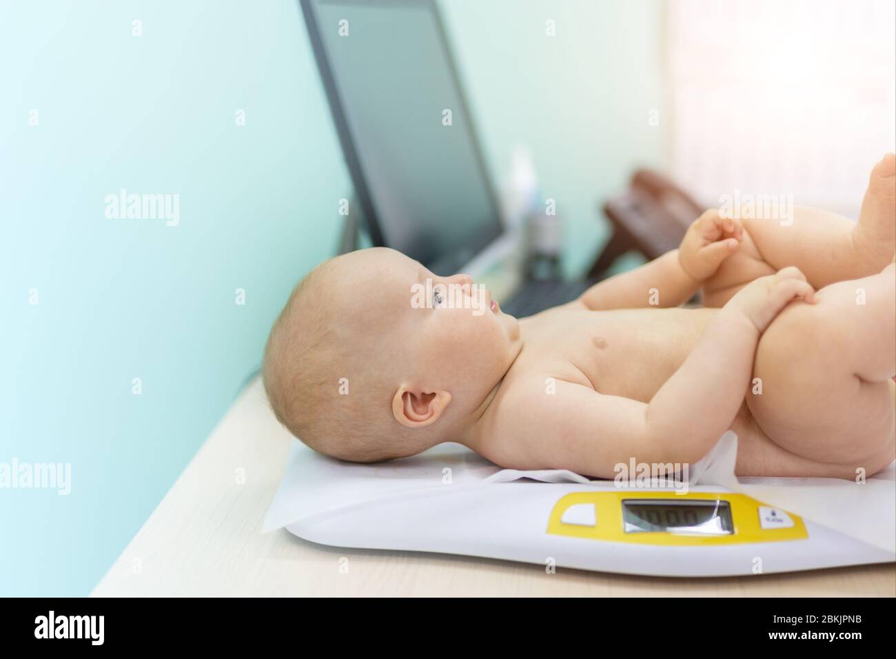 Pediatrician specialist taking measurement infant child weight during screening examination. Cute caucasian baby lying on electronic scales doctors Stock Photo