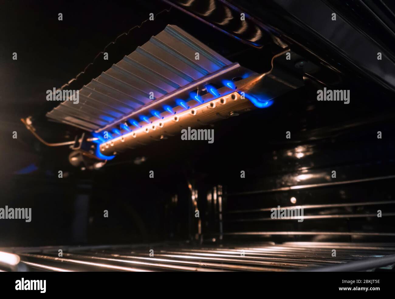 Oven inside with blue burner flames Stock Photo Alamy