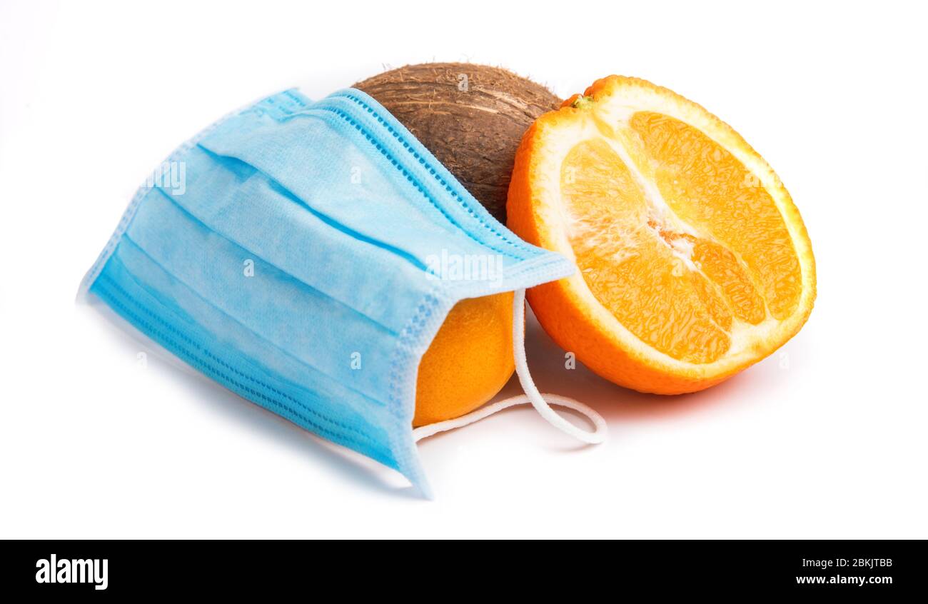 Medical disposable mask and orange with coconut on white background. Personal protective equipment against virus covid 19, epidemic and influenza. Stock Photo