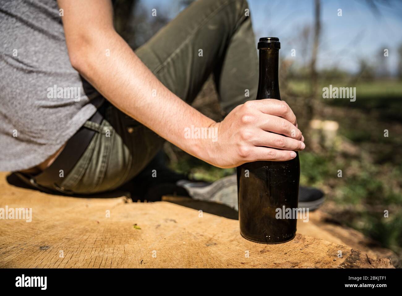 a bottle of wine in a man's hand, drinking alcohol in nature Stock Photo