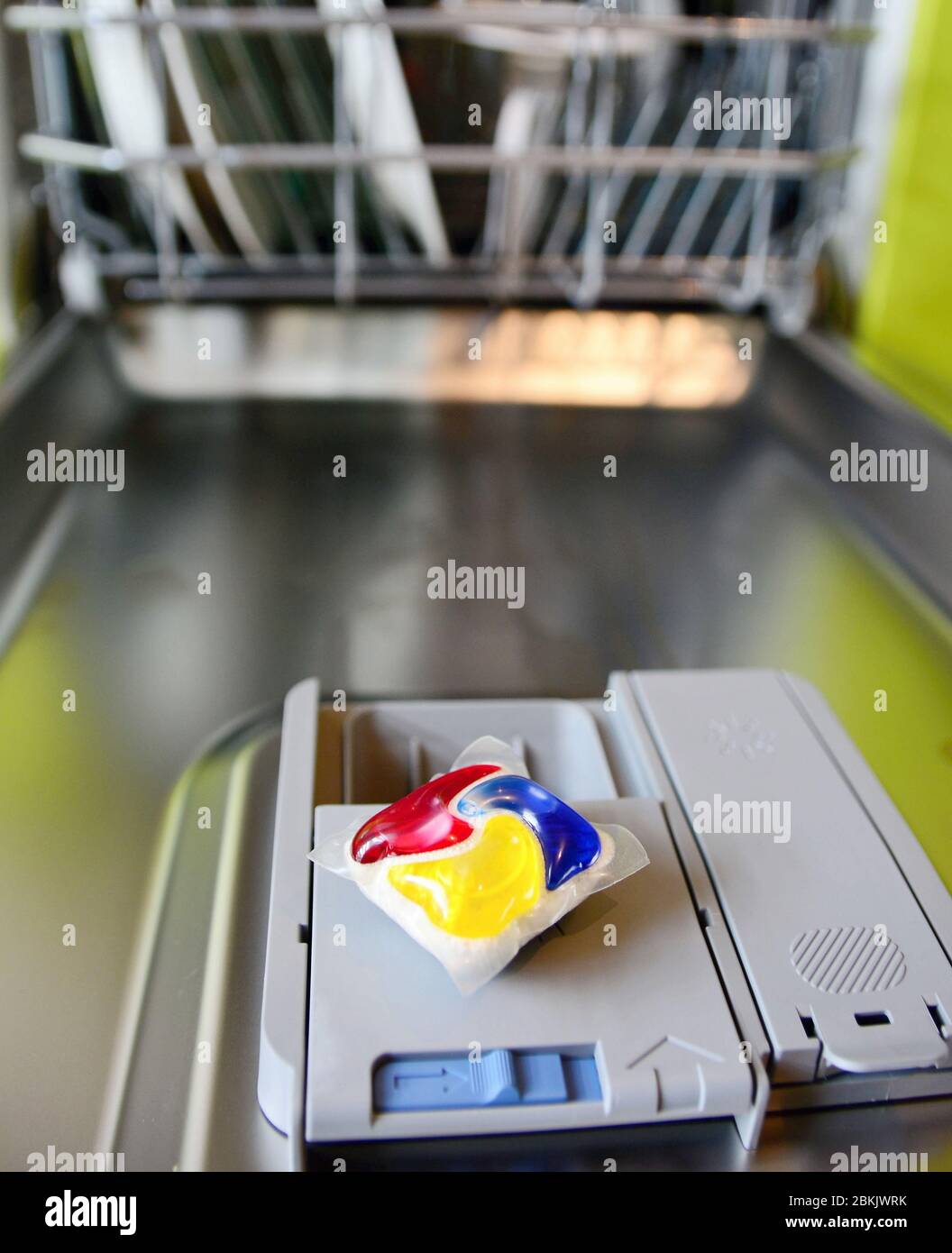 Closeup of detergent tablet put on the dishwasher tray in opened door