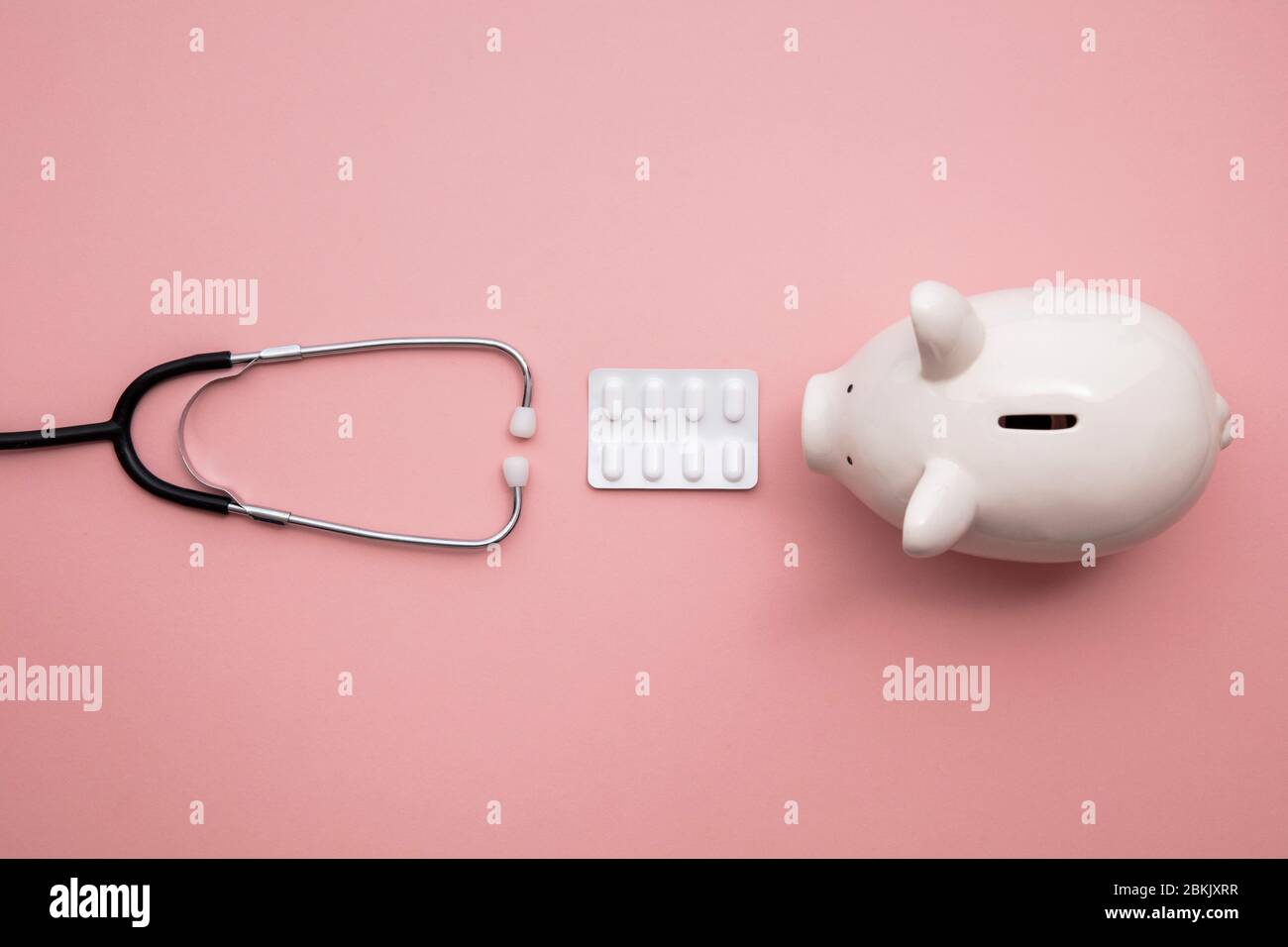 Healthcare finance. Medical stethoscope with piggy bank and pills Stock Photo