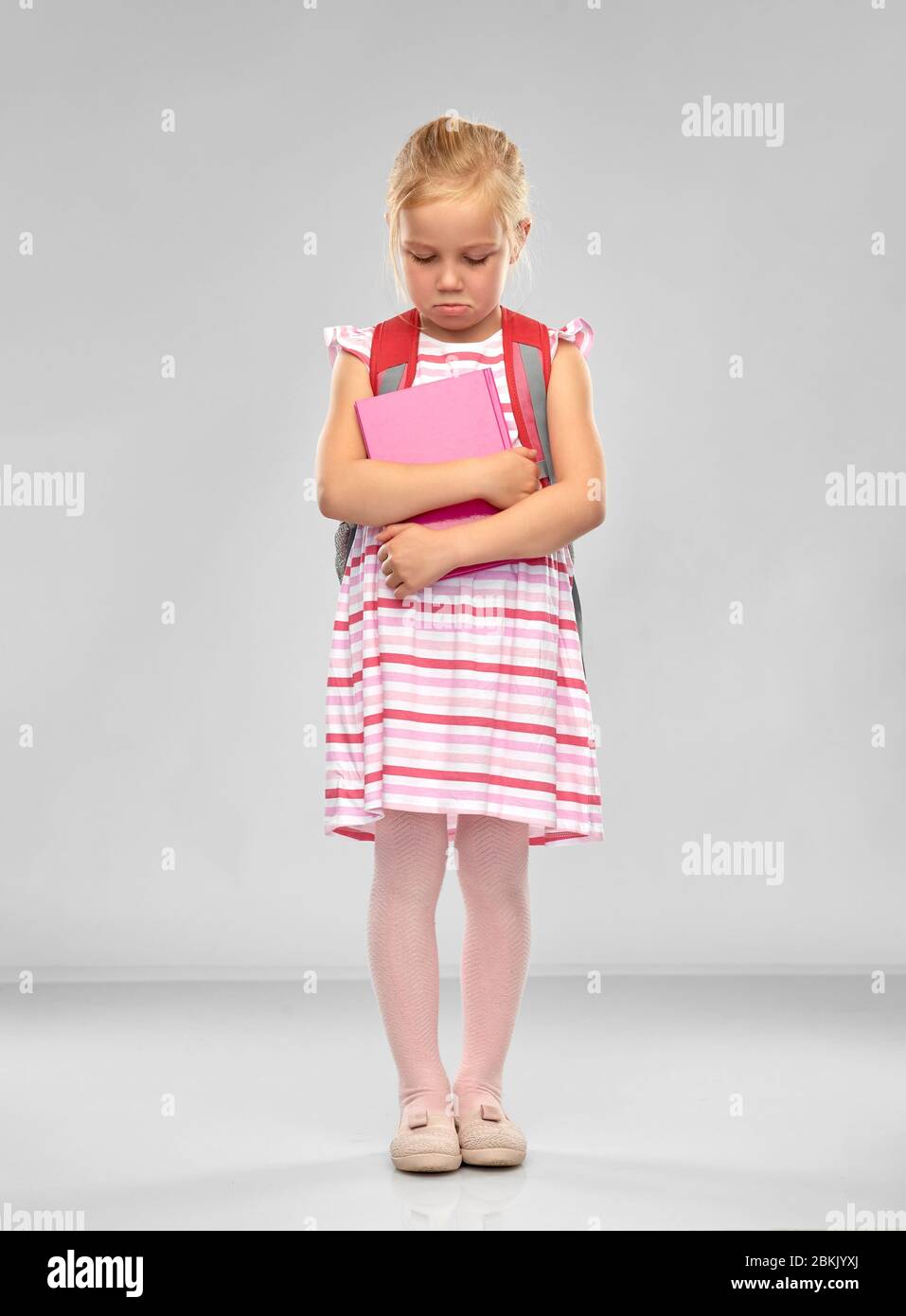 sad little student girl with school bag and book Stock Photo - Alamy