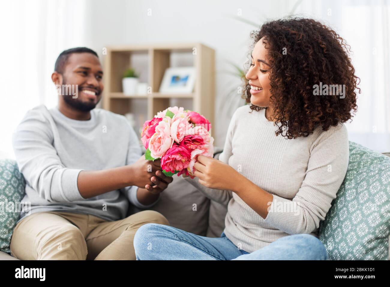 happy couple with bunch of flowers at home Stock Photo