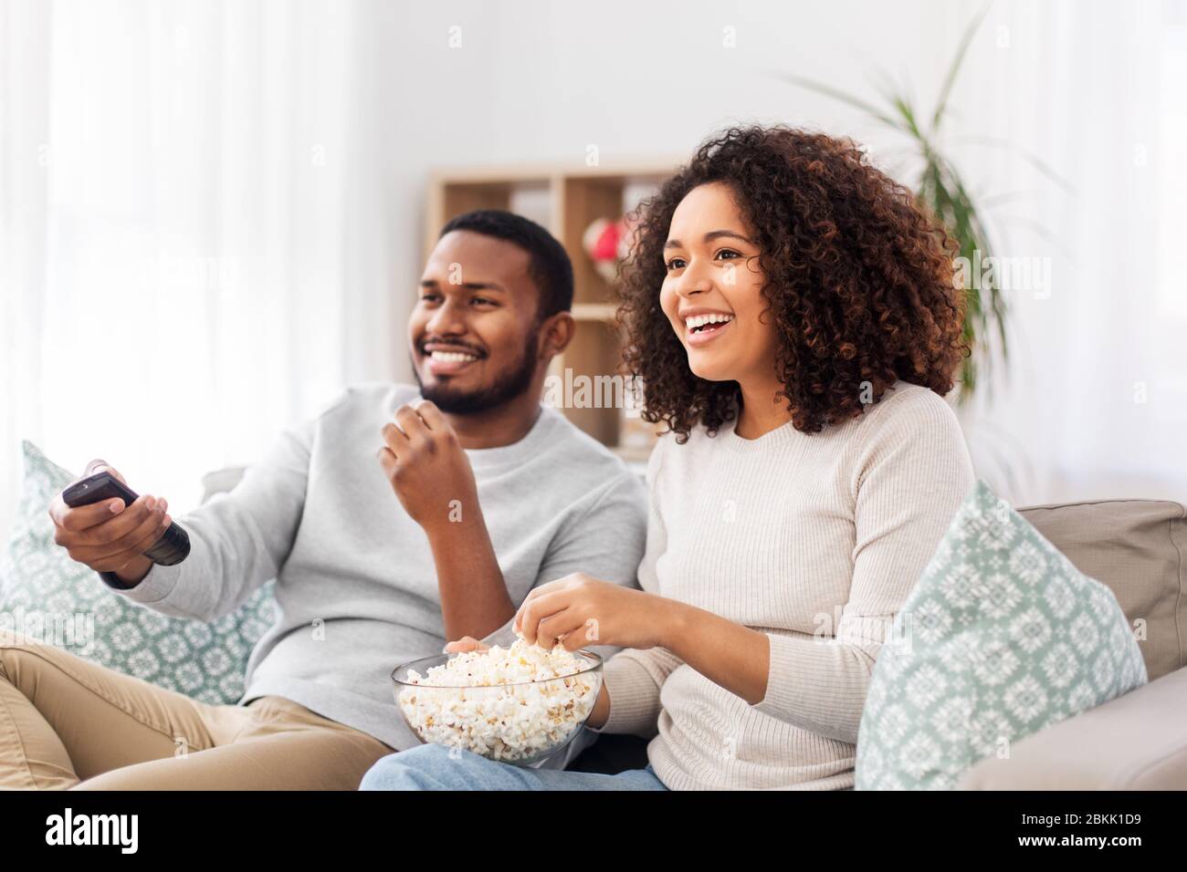 african couple with popcorn watching tv at home Stock Photo - Alamy