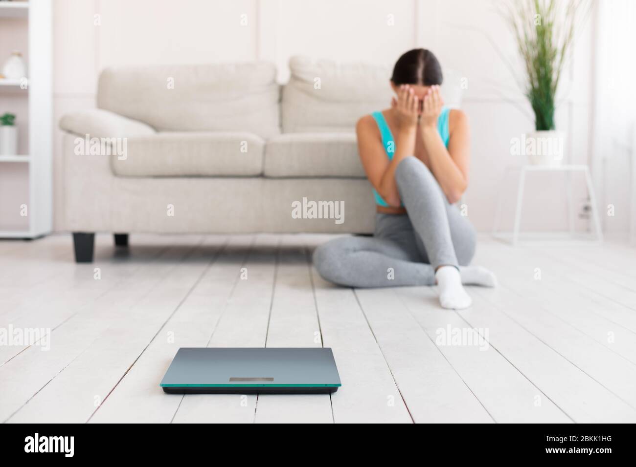 Woman Crying Sitting Near Weight Scales Gaining Kilograms At Home Stock Photo