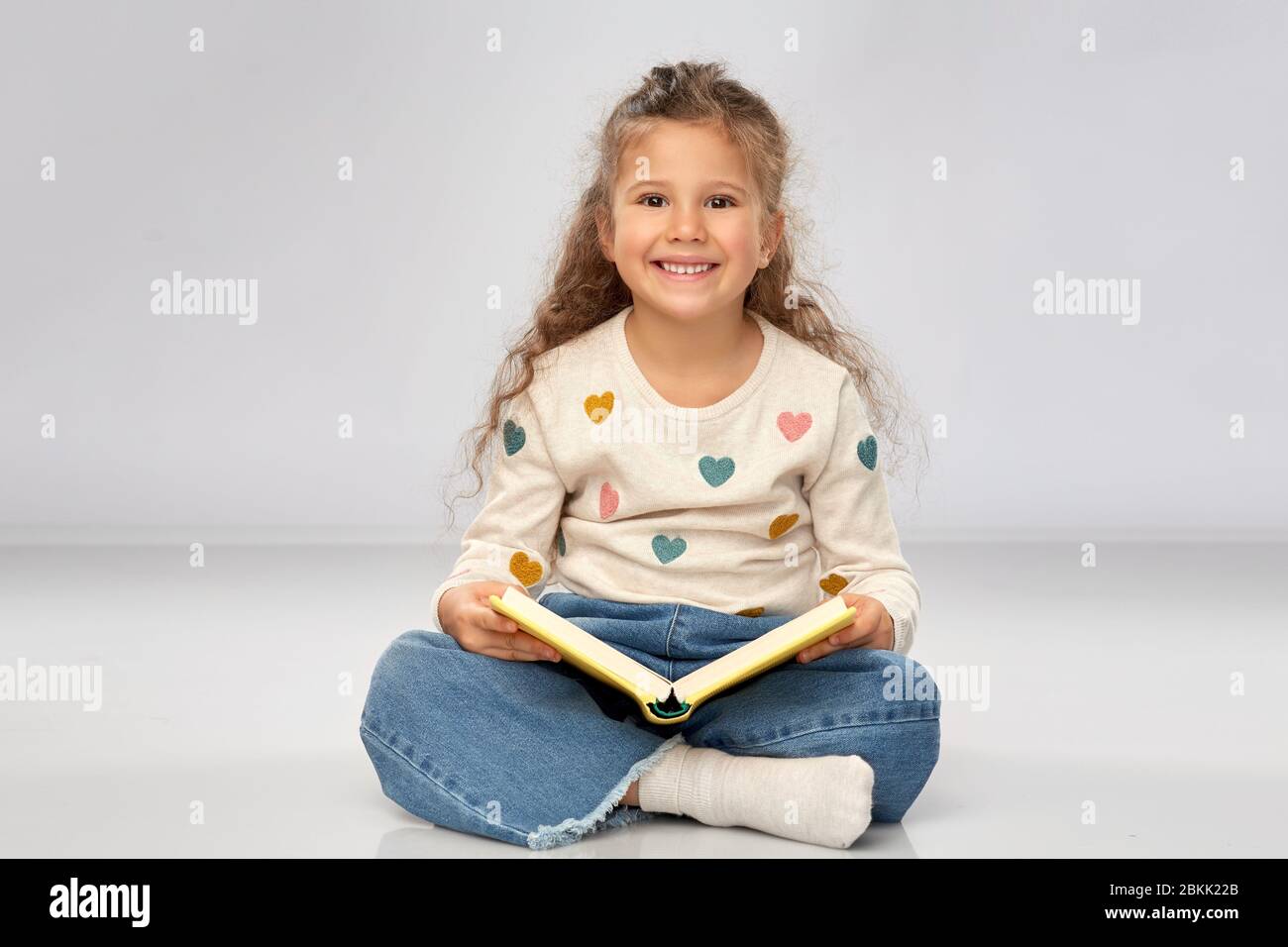 beautiful smiling girl reading book on floor Stock Photo - Alamy