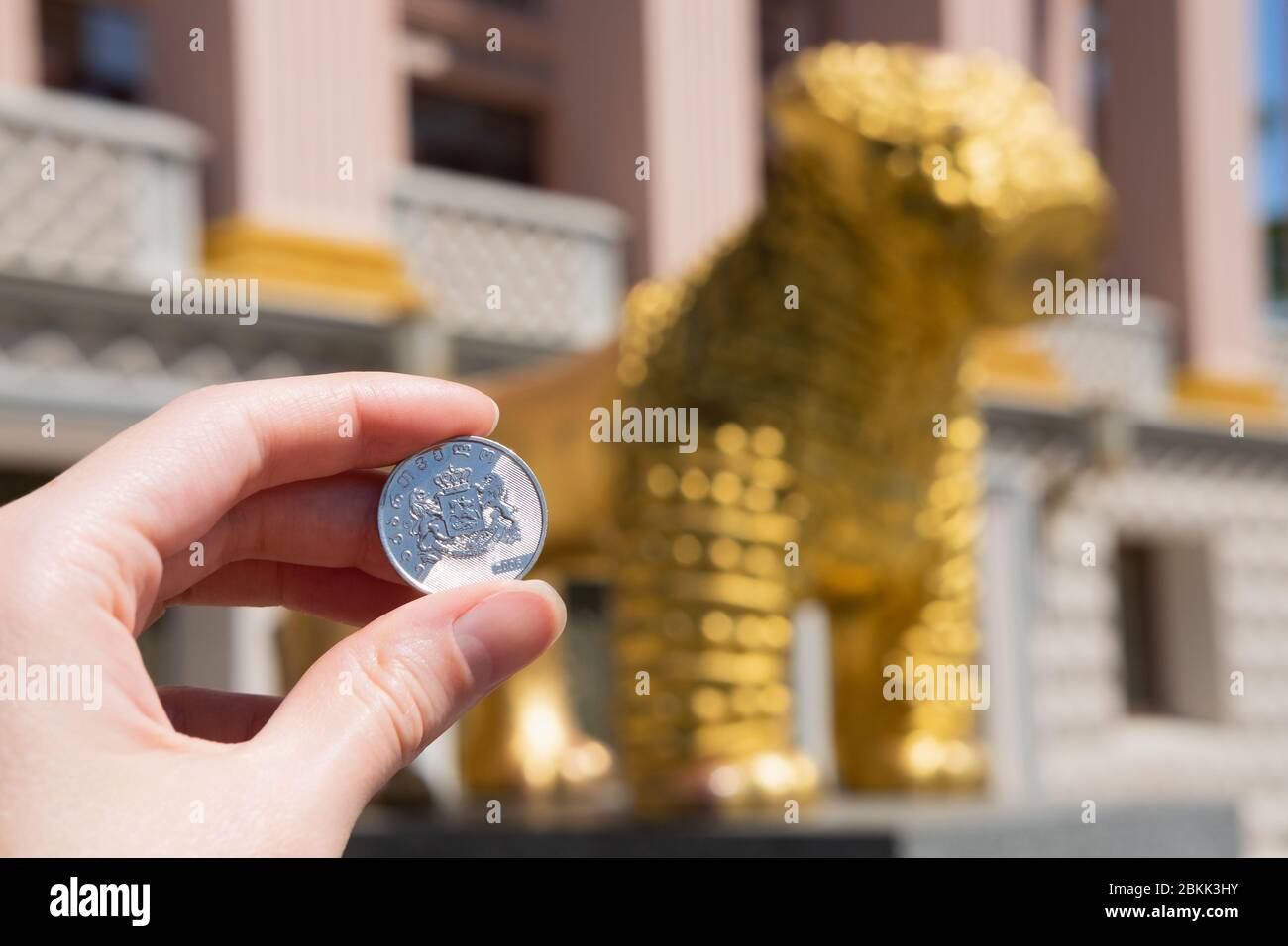 BATUMI, GEORGIA, Adjara - May 4 2020 Georgian Lari coin on a background of a golden lion - a national symbol in Georgia. Hand holds money in a tourist Stock Photo