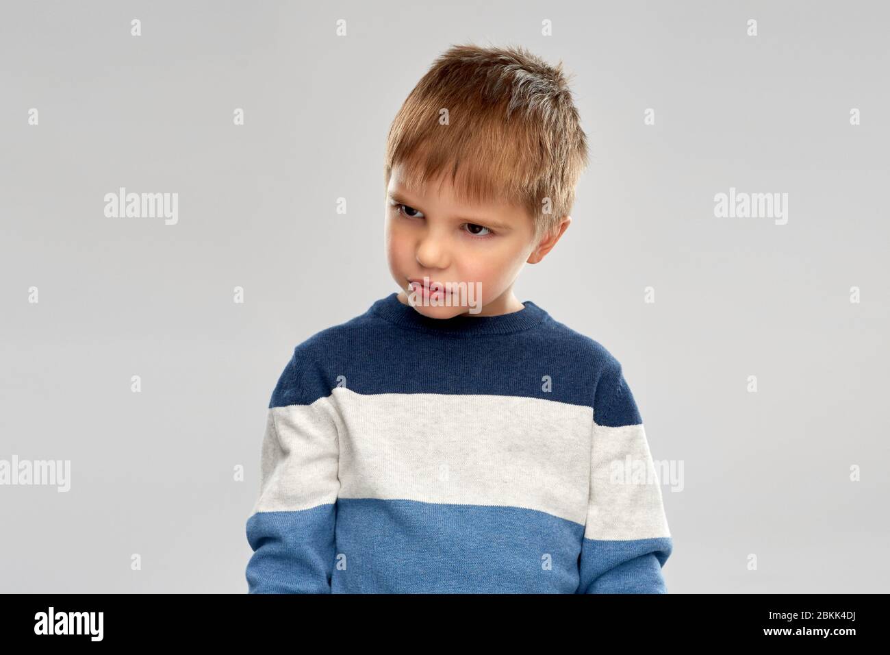 portrait of gloomy little boy in striped pullover Stock Photo