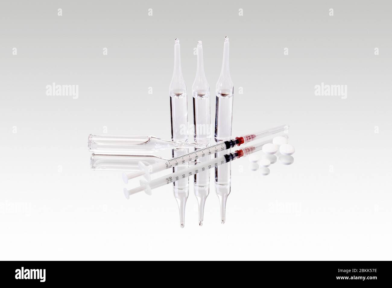 glass sealed medical ampoules with clear liquid, syringe and pills are