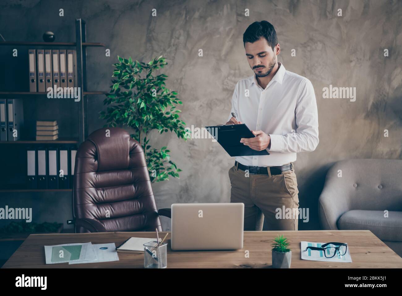 Portrait of his he nice attractive focused man skilled sales manager banker economist writing plan document at modern loft industrial style interior Stock Photo