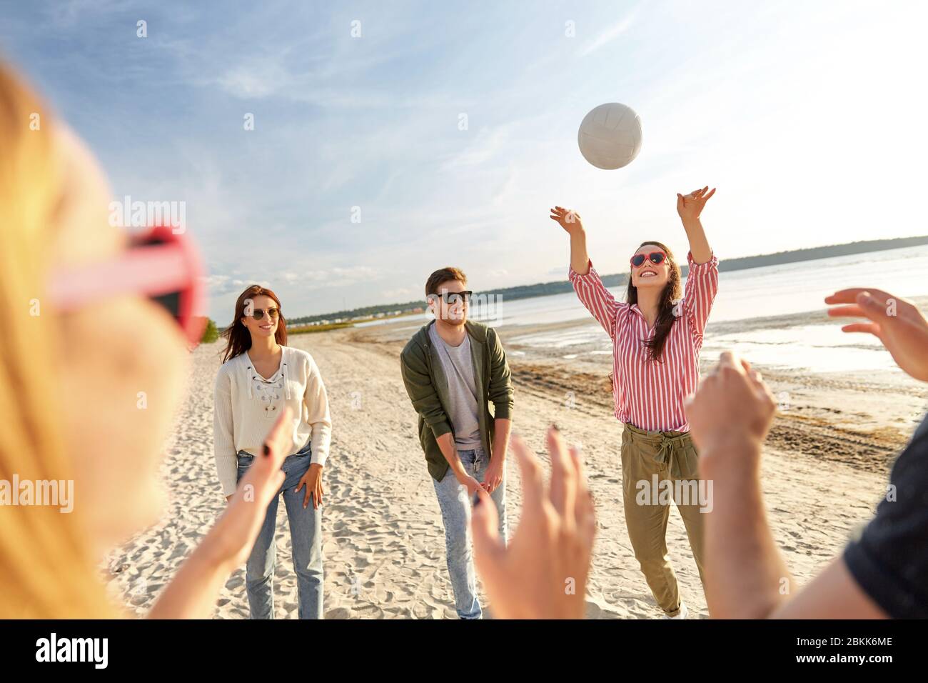 friends playing volleyball on beach in summer Stock Photo