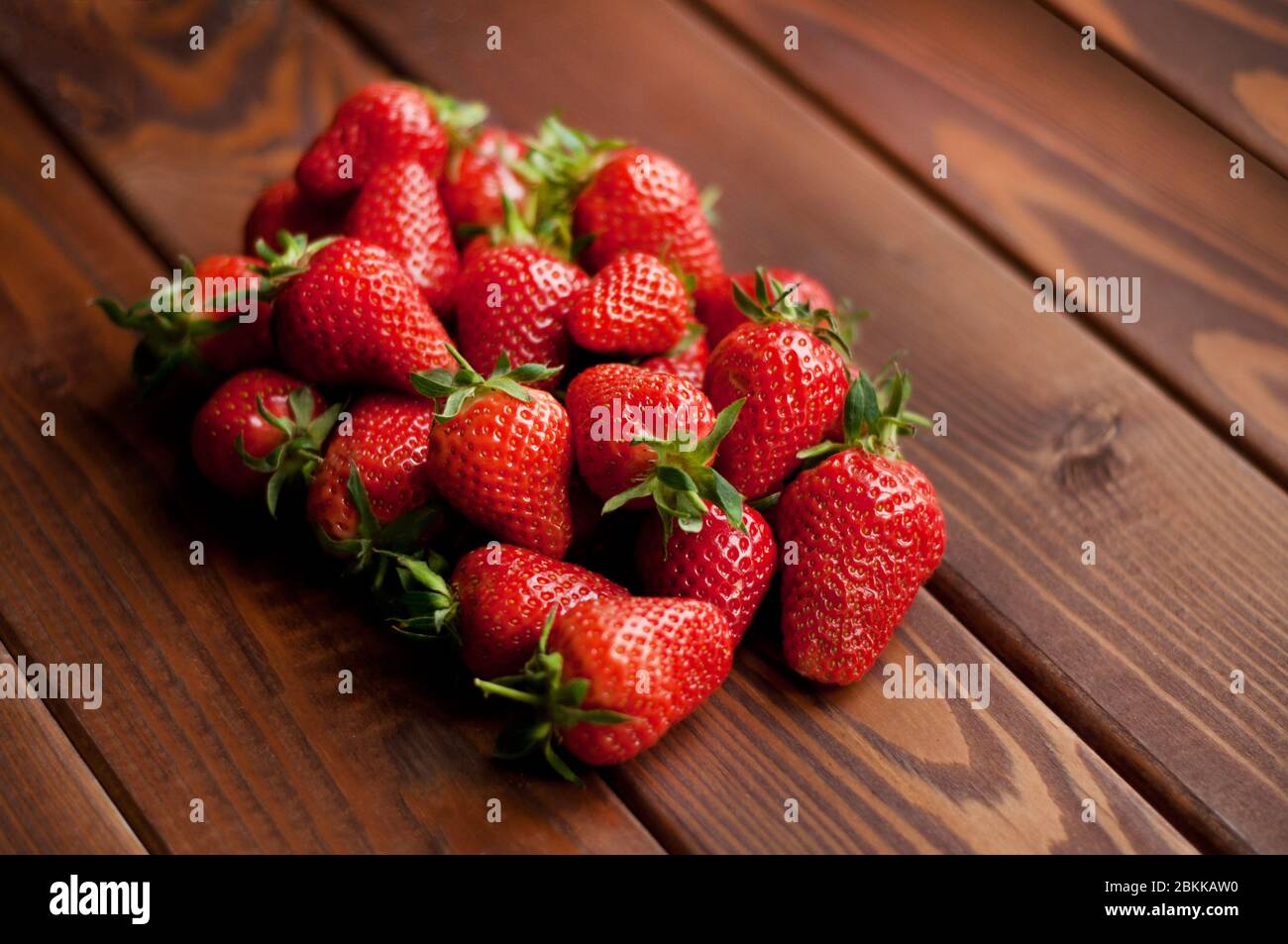 Ripe strawberries in craft paper on a wooden background. Healthy fresh food. Top view Stock Photo