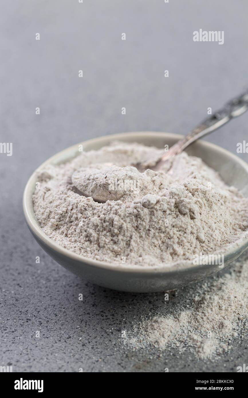 Glutenfree buckwheat flour for baking in the bowl on grey background Stock Photo